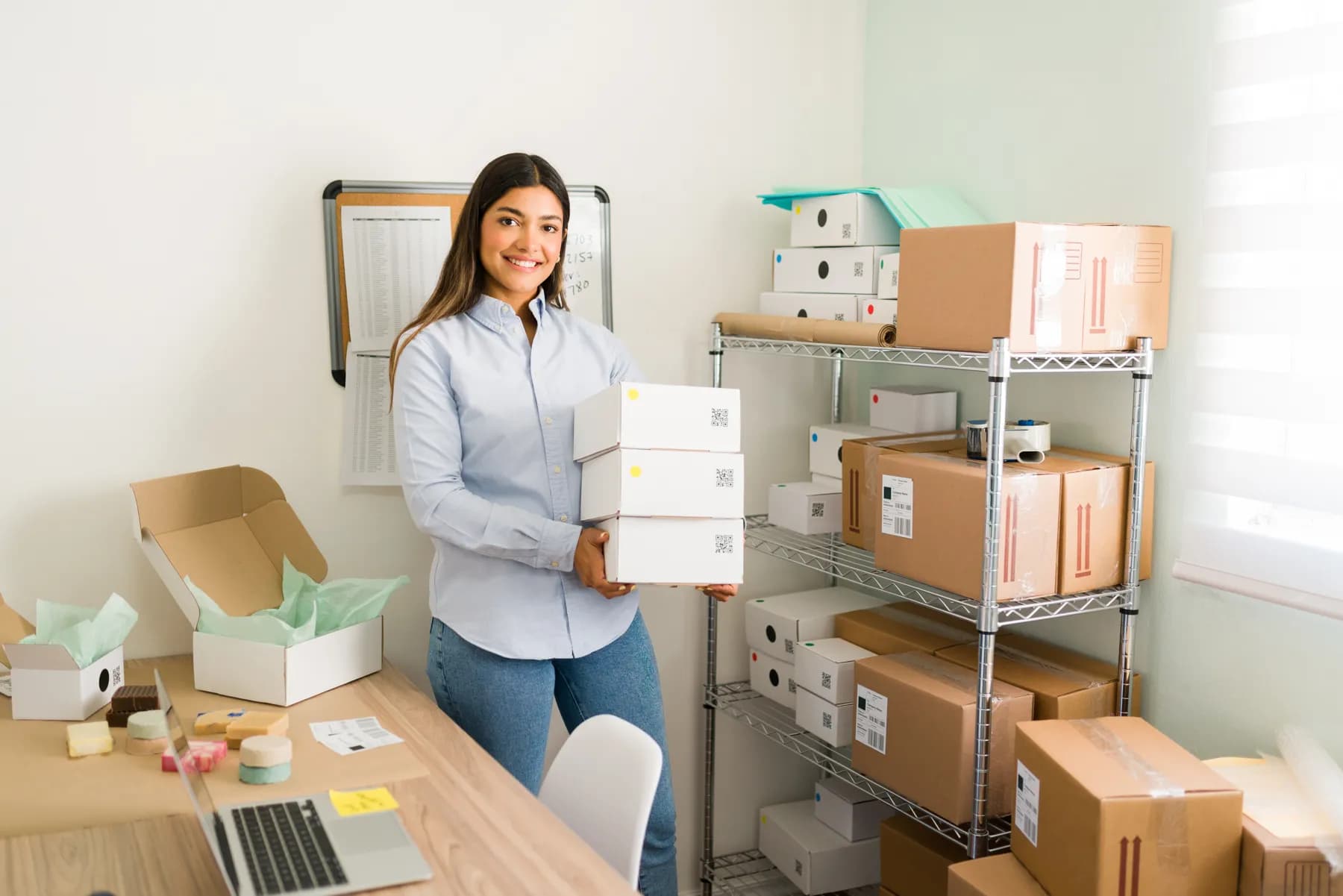 A founder smiling while packing orders in her small studio