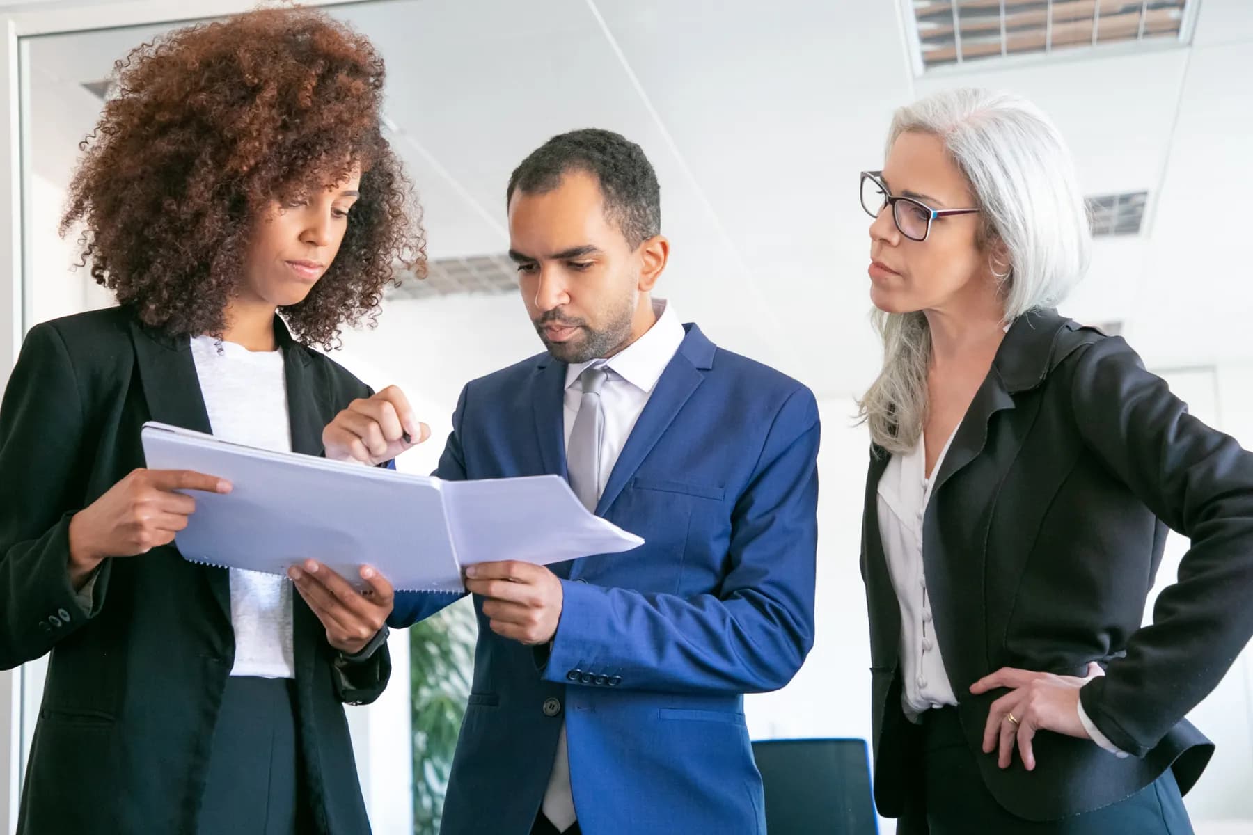 Three executives reviewing documents together in a meeting room